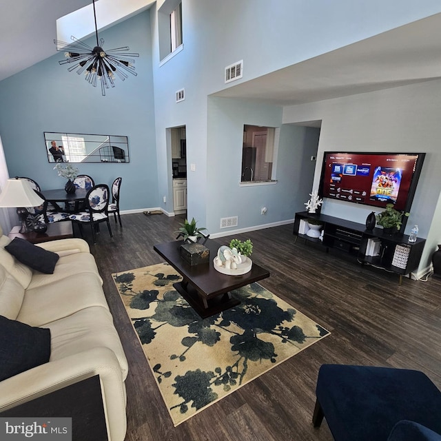 living room featuring dark wood-type flooring, a notable chandelier, and high vaulted ceiling