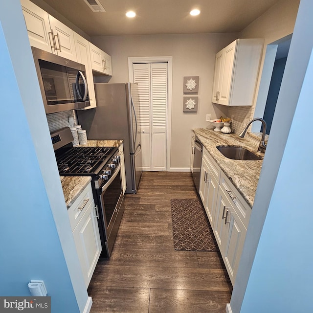 kitchen with appliances with stainless steel finishes, white cabinetry, sink, and dark hardwood / wood-style floors