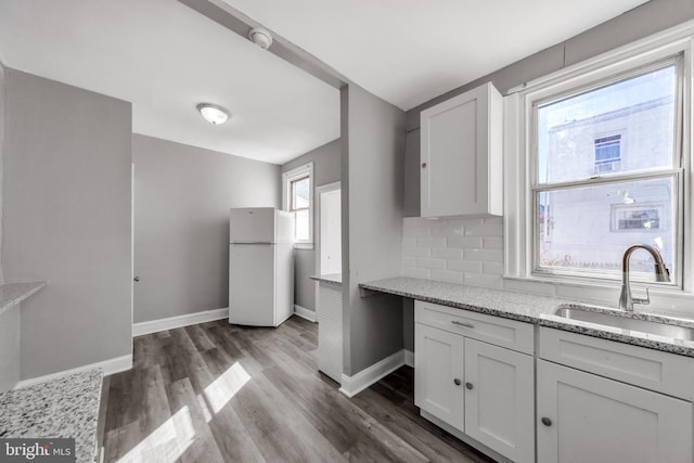 kitchen featuring white cabinetry, dark wood-type flooring, sink, light stone counters, and white refrigerator