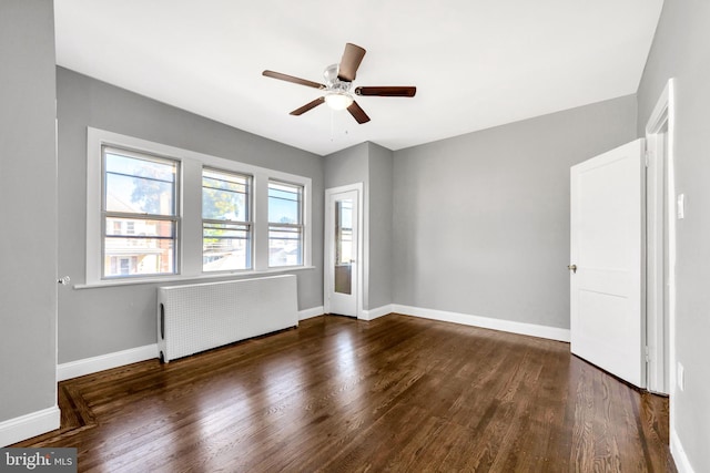 unfurnished room with radiator, ceiling fan, and dark wood-type flooring