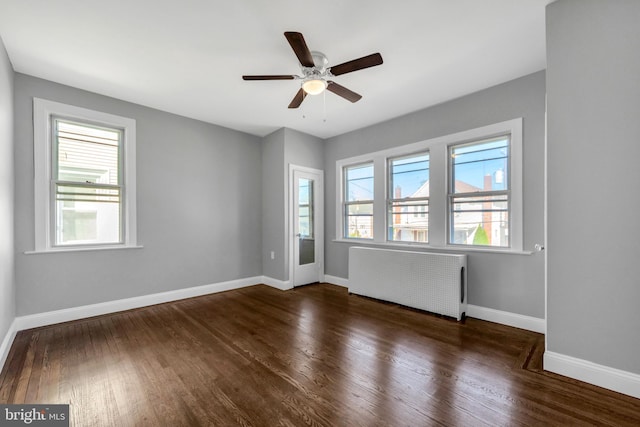 empty room featuring radiator heating unit, dark hardwood / wood-style floors, and ceiling fan