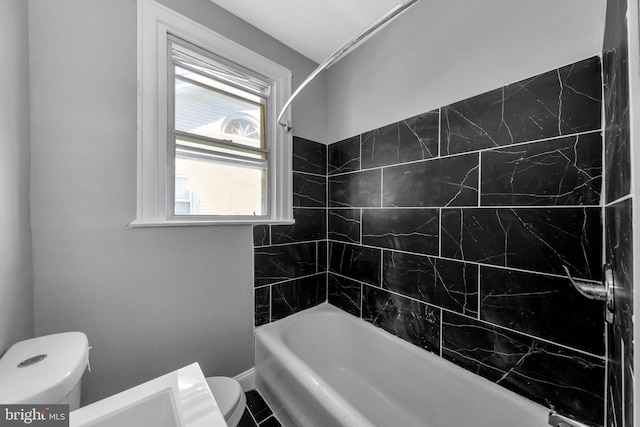 bathroom featuring toilet and tiled shower / bath