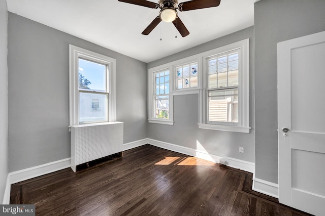 spare room with ceiling fan, radiator, and dark hardwood / wood-style flooring