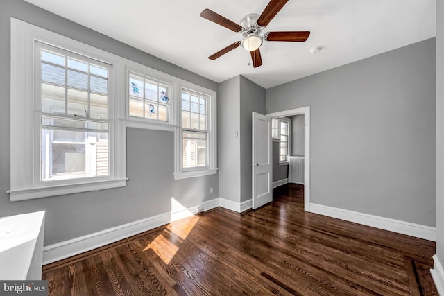 unfurnished bedroom with multiple windows, dark wood-type flooring, and ceiling fan