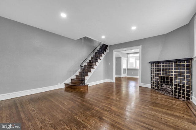 unfurnished living room featuring dark hardwood / wood-style floors and a tile fireplace