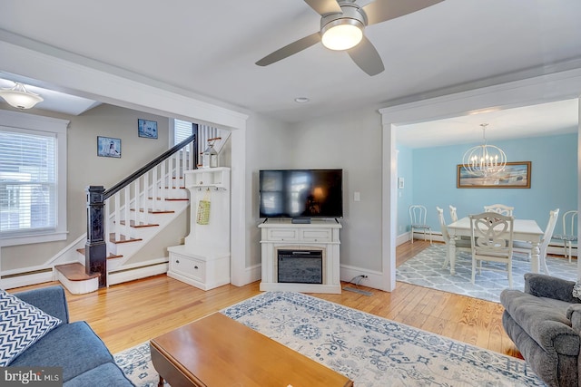 living room featuring ceiling fan with notable chandelier, wood-type flooring, and a baseboard radiator