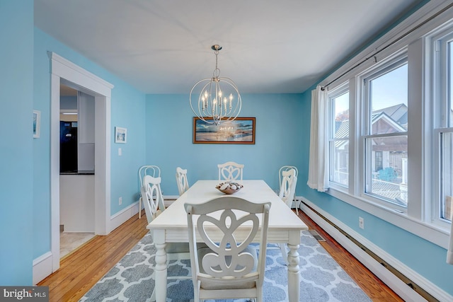 dining area featuring light hardwood / wood-style flooring, a chandelier, and baseboard heating