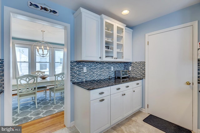 kitchen featuring pendant lighting, dark stone counters, decorative backsplash, and white cabinets