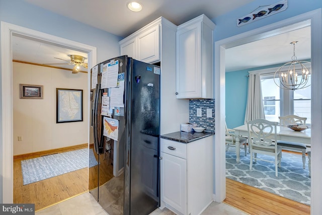 kitchen with dark stone countertops, tasteful backsplash, white cabinets, black fridge with ice dispenser, and light wood-type flooring