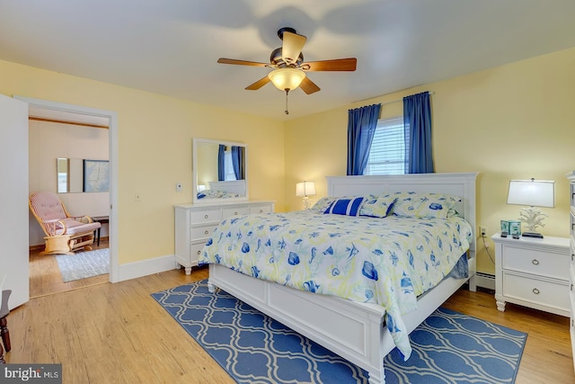 bedroom featuring light hardwood / wood-style flooring, ceiling fan, and baseboard heating