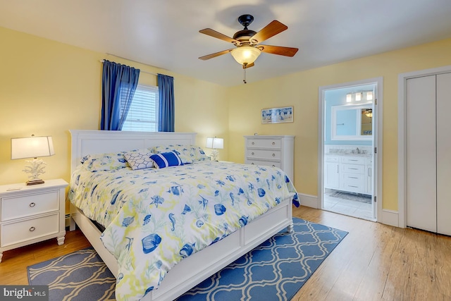 bedroom featuring a closet, connected bathroom, ceiling fan, and light hardwood / wood-style flooring