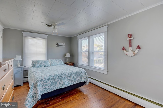 bedroom with crown molding, ceiling fan, baseboard heating, and light hardwood / wood-style floors