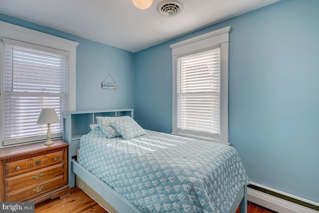 bedroom with a baseboard radiator and wood-type flooring