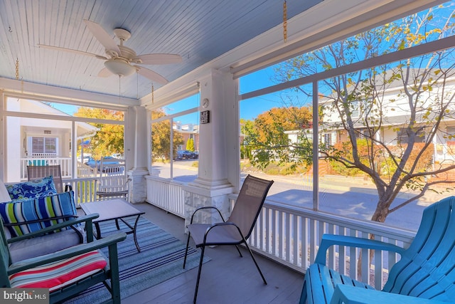 sunroom / solarium featuring decorative columns, wood ceiling, and ceiling fan