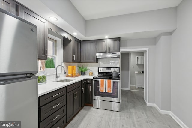 kitchen with appliances with stainless steel finishes, tasteful backsplash, dark brown cabinetry, sink, and light hardwood / wood-style floors