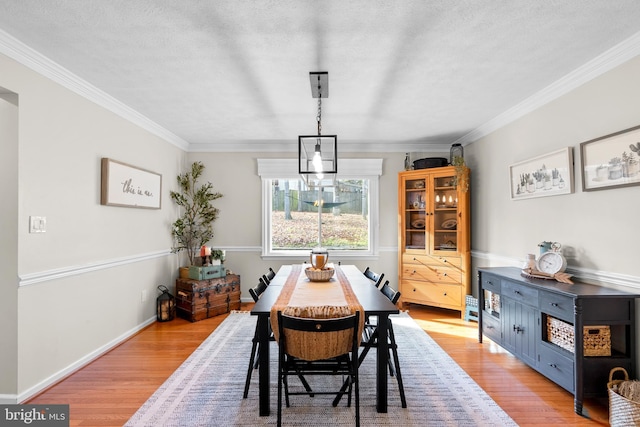 dining room featuring a textured ceiling, light wood-type flooring, and crown molding