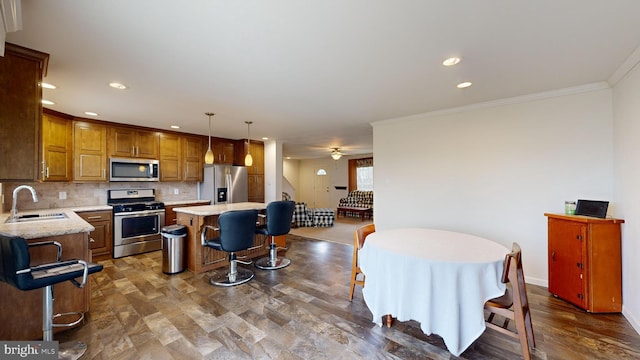 kitchen with backsplash, stainless steel appliances, sink, a center island, and hanging light fixtures