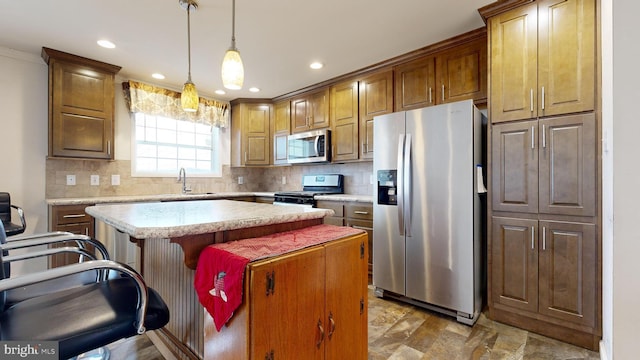 kitchen with a center island, a kitchen breakfast bar, sink, appliances with stainless steel finishes, and decorative light fixtures