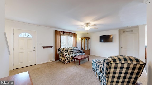 living room featuring ceiling fan, light carpet, and ornamental molding