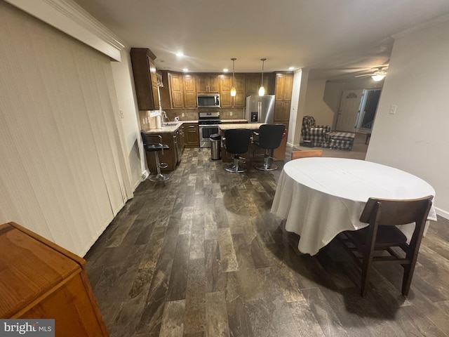 dining space with ceiling fan, sink, and dark wood-type flooring