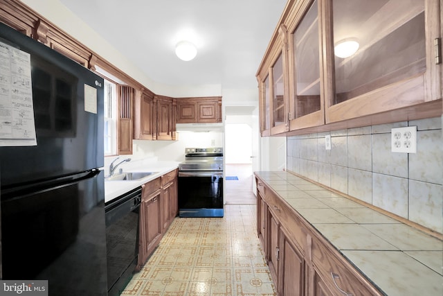 kitchen with black appliances, tile countertops, backsplash, and sink