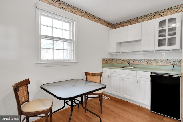 kitchen featuring light hardwood / wood-style floors, white cabinetry, sink, and black dishwasher