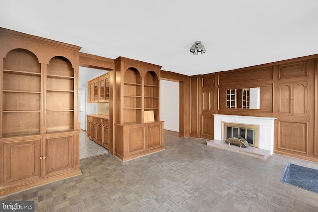 unfurnished living room featuring built in shelves and parquet flooring