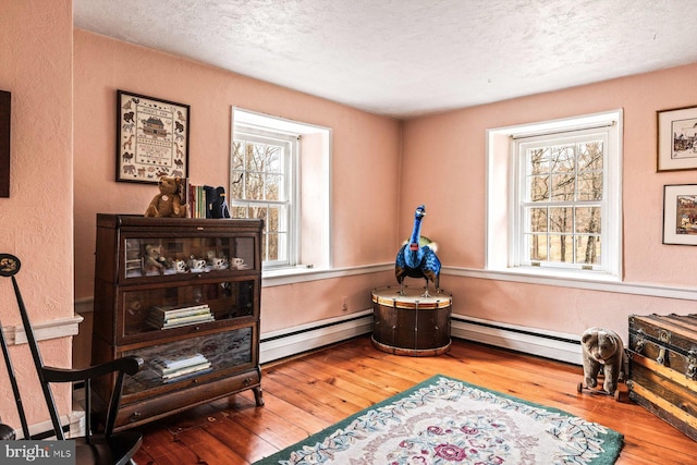 sitting room with baseboard heating, hardwood / wood-style floors, and plenty of natural light