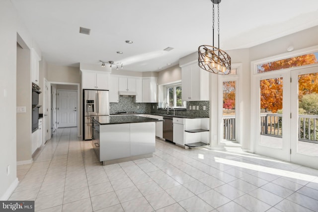 kitchen featuring white cabinets, pendant lighting, tasteful backsplash, a center island, and stainless steel appliances