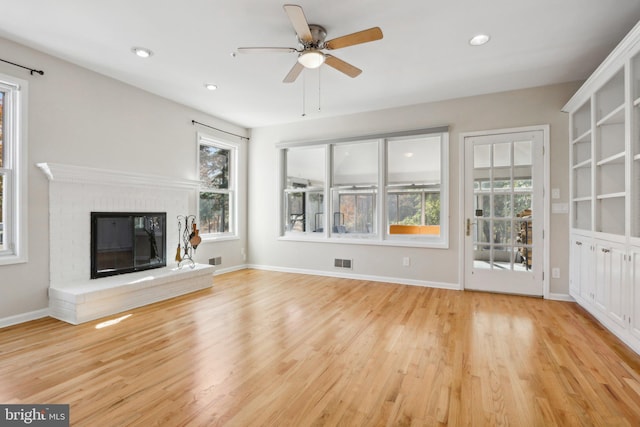 unfurnished living room with ceiling fan, light hardwood / wood-style floors, and a brick fireplace