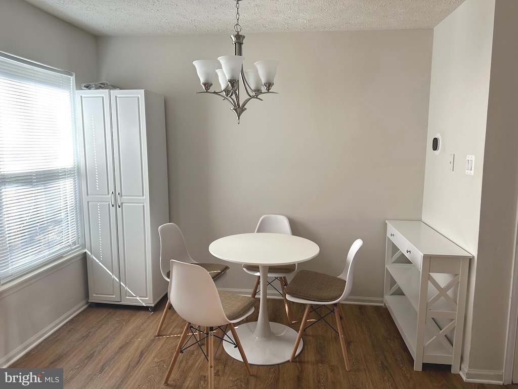 dining area with a chandelier, dark wood-type flooring, and a textured ceiling