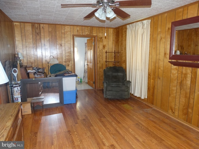 home office featuring hardwood / wood-style flooring, wood walls, and ceiling fan