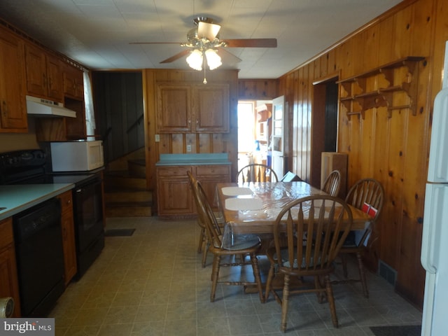 dining area with ceiling fan and wooden walls