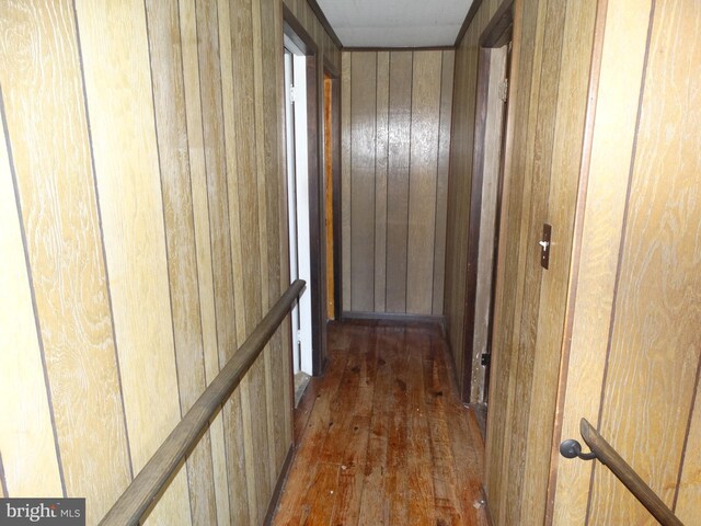 hallway with dark hardwood / wood-style floors and wood walls