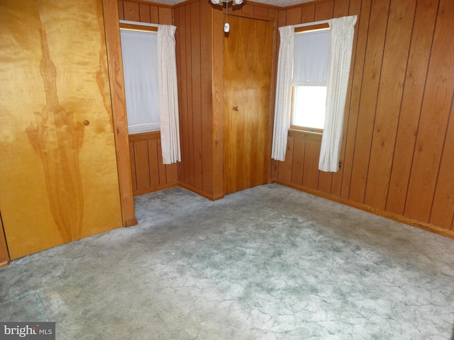 spare room featuring wood walls and light colored carpet