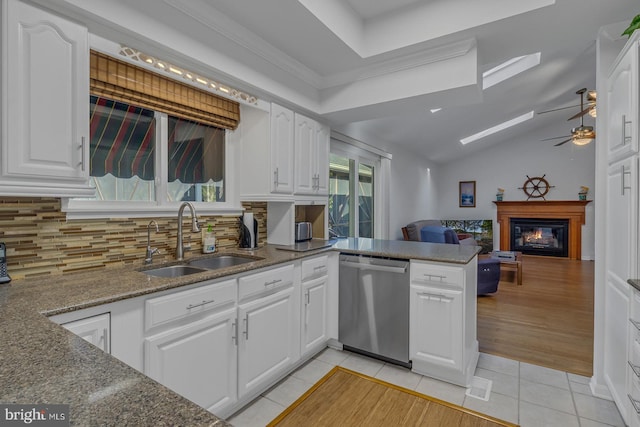 kitchen with sink, kitchen peninsula, white cabinetry, stainless steel dishwasher, and decorative backsplash