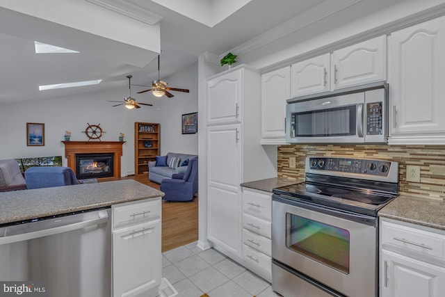 kitchen with lofted ceiling, decorative backsplash, appliances with stainless steel finishes, and white cabinets