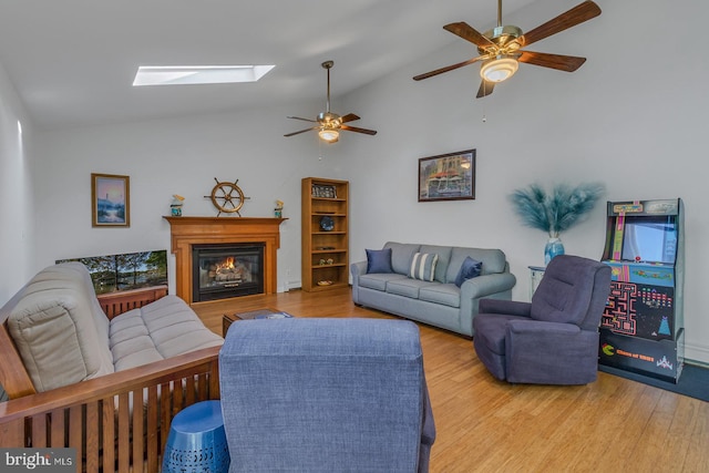 living room with ceiling fan, high vaulted ceiling, a skylight, and light wood-type flooring