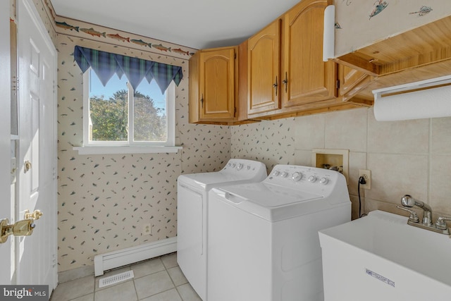 washroom featuring washer and dryer, sink, baseboard heating, cabinets, and light tile patterned floors