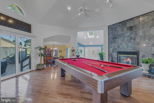 rec room with a tiled fireplace, a healthy amount of sunlight, wood-type flooring, and billiards