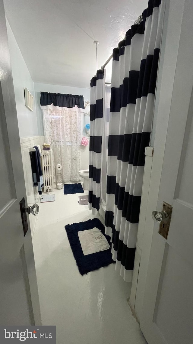 bathroom with a shower with shower curtain, toilet, and concrete floors