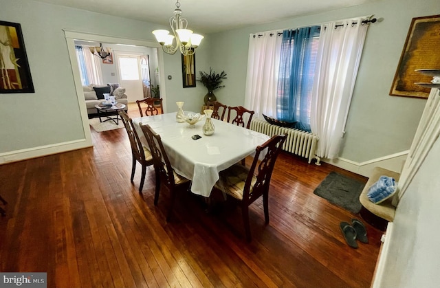 dining area featuring dark wood-type flooring, radiator, and an inviting chandelier