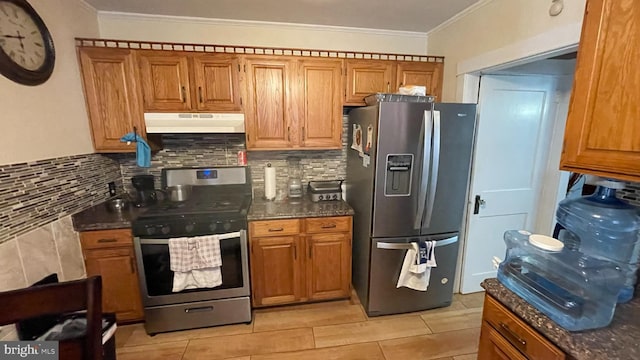 kitchen featuring appliances with stainless steel finishes, dark stone counters, decorative backsplash, light tile patterned floors, and ornamental molding