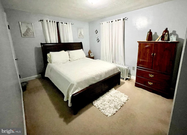 carpeted bedroom featuring radiator heating unit and a textured ceiling