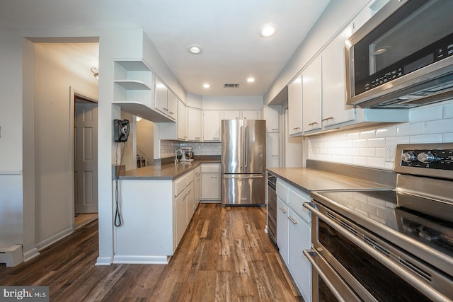 kitchen with white cabinets, appliances with stainless steel finishes, tasteful backsplash, and dark wood-type flooring