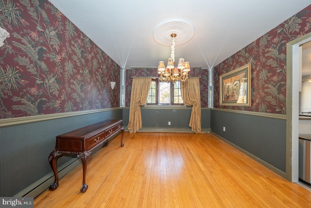 unfurnished dining area featuring a chandelier, wood-type flooring, and baseboard heating