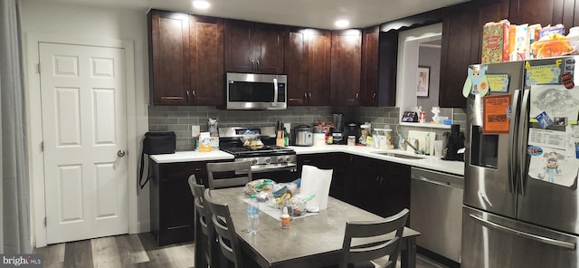 kitchen featuring decorative backsplash, stainless steel appliances, sink, and light wood-type flooring