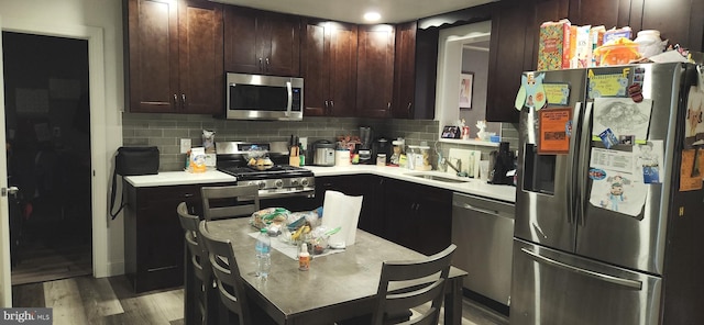 kitchen featuring sink, backsplash, dark brown cabinets, stainless steel appliances, and light hardwood / wood-style flooring