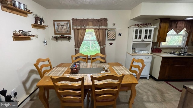 dining space featuring a baseboard radiator, a textured ceiling, and sink