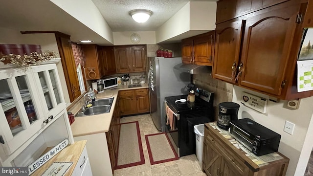 kitchen with black range with electric cooktop, sink, a textured ceiling, and backsplash